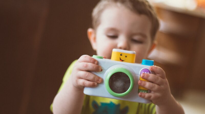toddler holding white camera toy